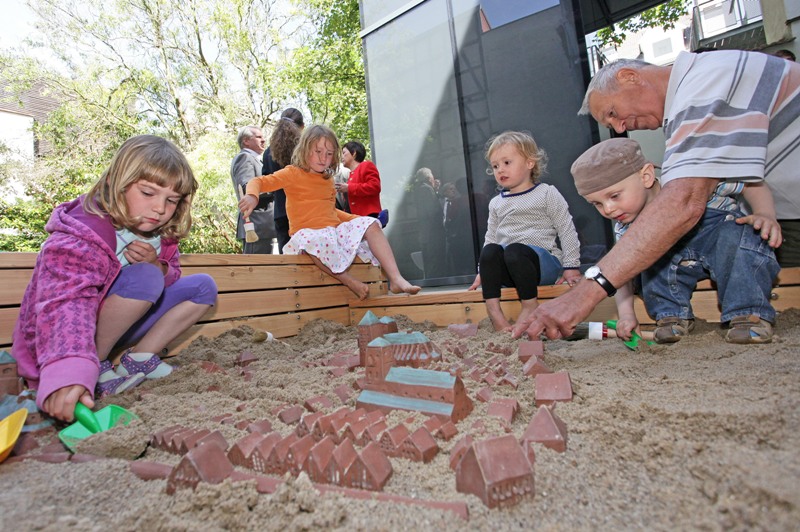 kleine Schatzgräber im Sandkasten mit Altstadtmodell zum Ausgaben